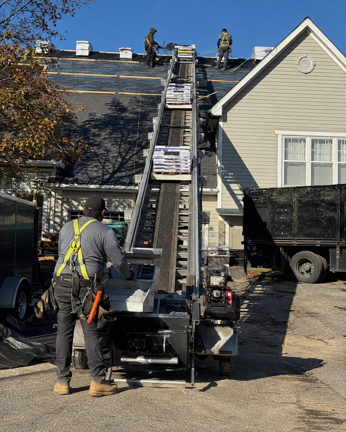 Roofing crew loading shingle bundles onto a residential roof