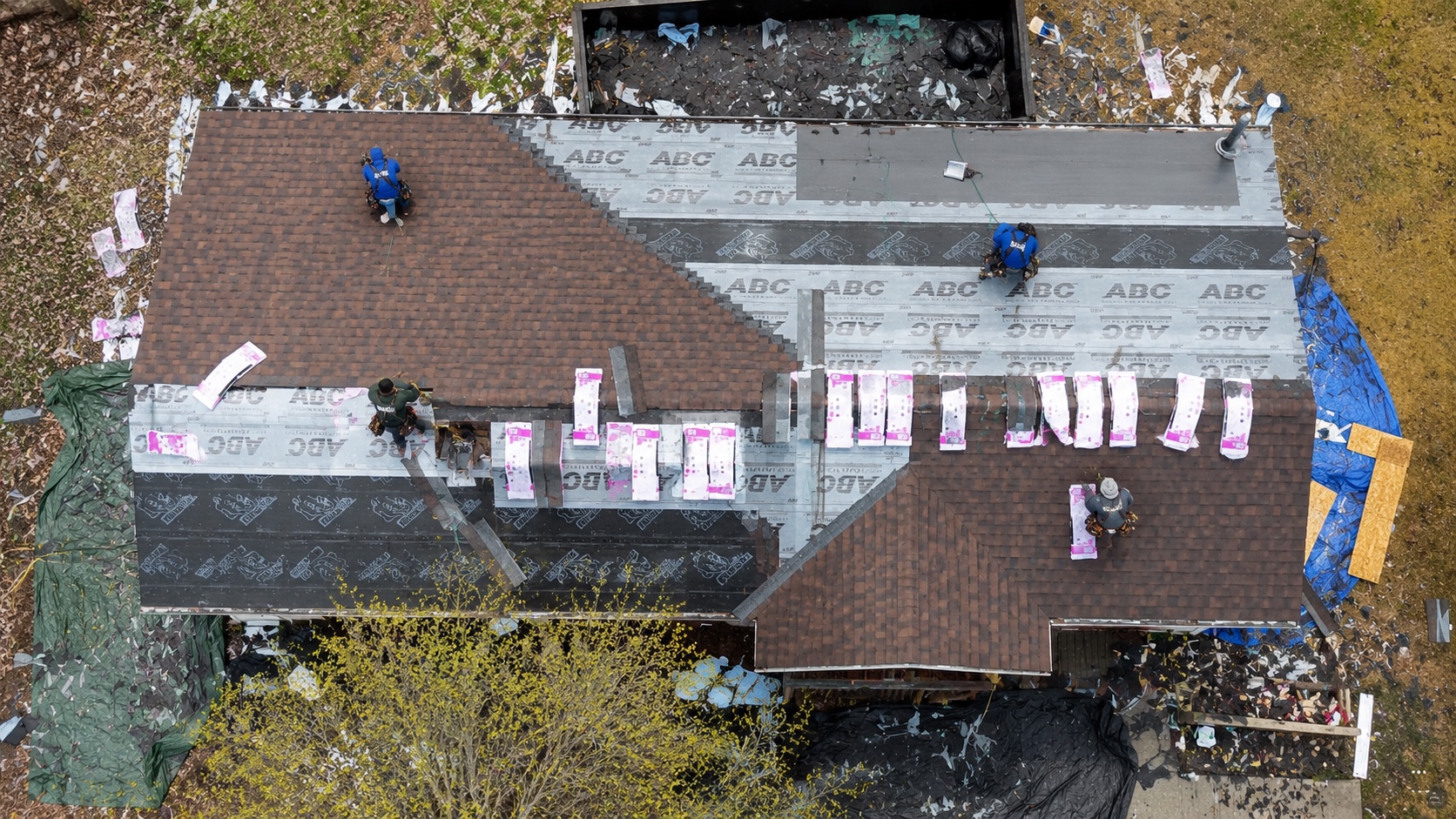 Residential roofing crew replacing shingles viewed from above